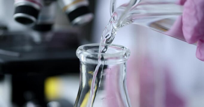 Scientist pours clear liquid into flask slow motion 4k movie