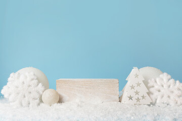 White cube pedestal on snow, winter festive blue background. Light Christmas scene with a podium. Display of cosmetics and beauty products. Stand with white New Year's decor