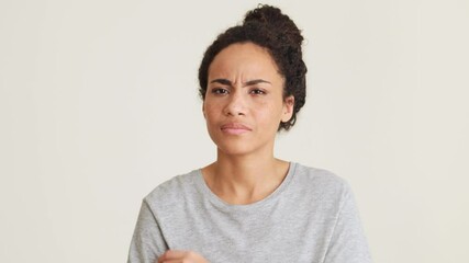 Displeased African woman in t-shirt disagree with something in the grey studio