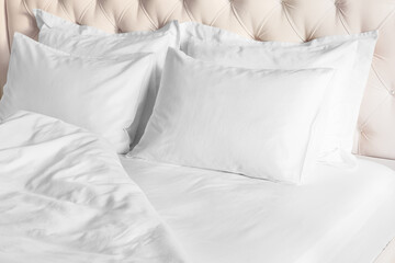 White pillows, duvet and duvet case on bed with beige headboard.