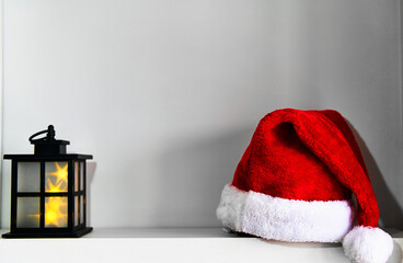 Obraz na płótnie Canvas Minimalist Christmas home decor concept. Santa Claus hat by lantern over shelf 