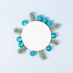 Christmas layout made with blue Christmas baubles and fir branches on pastel blue background. New Year aesthetic composition with copy space.