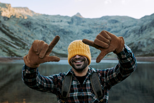 Unrecognizable man showing frame gesture near lake