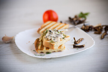 fried bread toast with cheese spread with boiled dried mushrooms on a wooden table.