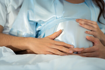 Pregnant woman with husband in bedroom with the atmosphere of having fun talking
