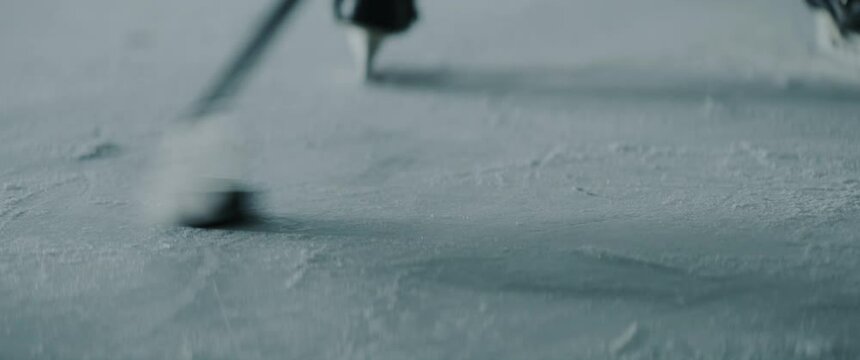 MED Professional ice hockey player practices stickhandling on the indoor rink alone. Shot with 2x anamorphic lens