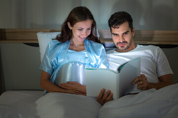 Pregnant woman with husband in bedroom Reading fairy tales to the baby in the womb