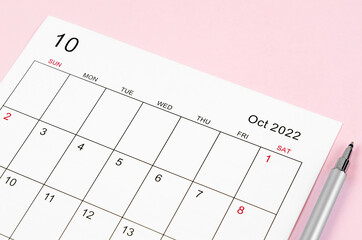 October 2022 calendar sheet with pen on pink background.