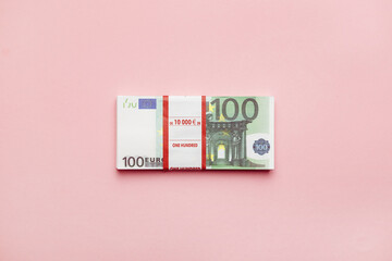Bank bundle of 100 euro banknotes on pink background, money minimalism top view.