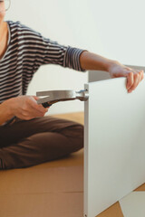 Close-up of a woman's hands driving a nail with a hammer.