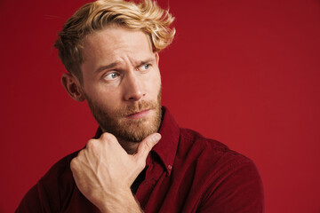 White bearded man holding his chin while looking at camera