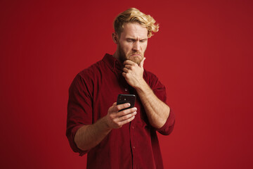 White puzzled man wearing shirt using mobile phone