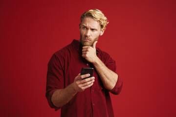White puzzled man wearing shirt using mobile phone