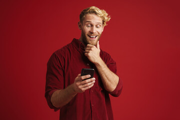 White bearded man wearing shirt laughing and using cellphone