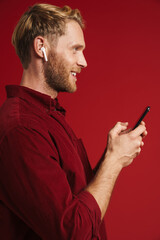 Blonde man listening music with earphones and using cellphone