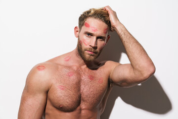 White shirtless man with lipstick marks looking at camera