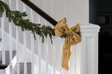 Holiday Christmas stairway stairs decor of green garland and gold glitter bows for a festive Christmas or New Year's party celebration