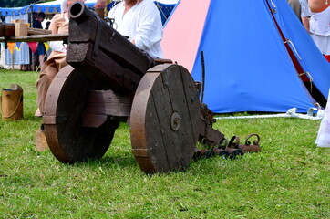Obraz premium A close up on a big wooden bombard or cannot with a barrel, wheels and body made out of wooden planks and logs and with some metal enforcing elements seen on a sunny summer day in Poland