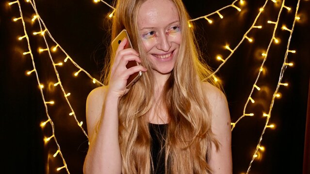 Lesbian, woman, bisexual, albino with rainbow makeup talking on the phone and celebrates Merry Christmas and Happy New Year, gay parade, Bisexuality Day or National Coming Out Day in the month of