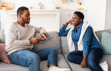Black couple talking and spending time together resting on couch
