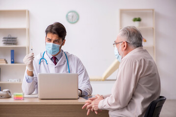 Obraz premium Old male patient visiting young male doctor in vaccination conce