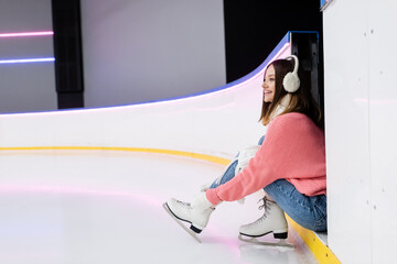 young smiling woman tying shoe laces on ice skates.