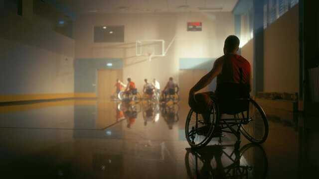 Wheelchair Basketball Game: Player Wearing Red Shirt Holding Ball Waiting for His Turn. Athlete Watching His Team Play. Determination, Motivation of People with Disability Excelling at the Sport.