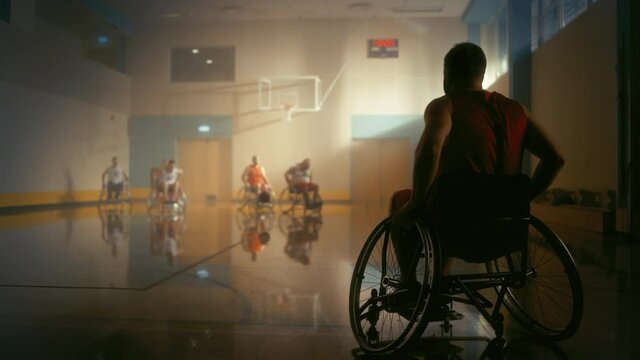 Wheelchair Basketball Game: Player Wearing Red Shirt Holding Ball Joins the Game. Athlete Watching His Team Play. Determination, Motivation of People with Disability Excelling at the Sport.