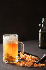 Glass of beer and pistachios on a plate on a dark background