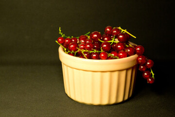 Red currant in a pink bowl on black background close up,summer dessert,image for poster,wall canvas,horizontal cover design,home decor,vegetarian diet,ingredient for cooking,tasty useful snack