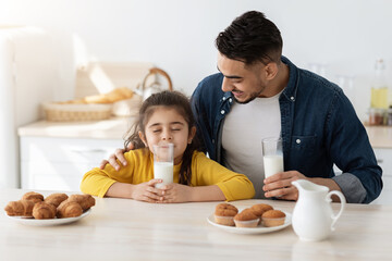 Obraz na płótnie Canvas Cute Little Arab Girl Enjoying Drinking Milk While Having Snacks With Daddy