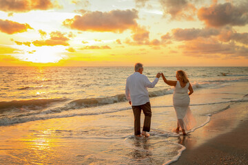 Couple enjoy their walk along beach together after elopement ceremony with sunset in background for these silhouette images.