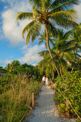 Couple walk along palm tree lined path to a secluded beach for their elopement ceremony on Sanibel Island