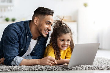 Distance Learning. Cute Little Girl And Arab Dad Using Laptop At Home
