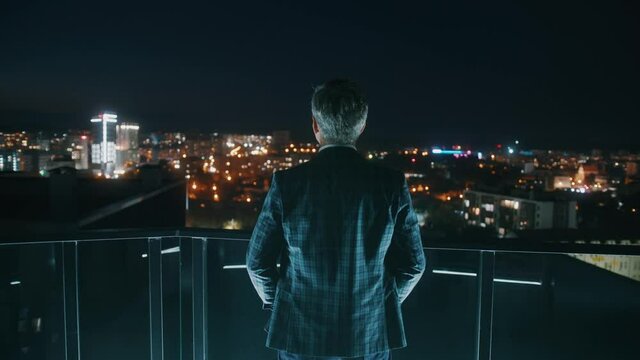 Close up shot back businessman in suit stand on balcony at night. Silhouette. Skyline. Think. Building. Slow motion