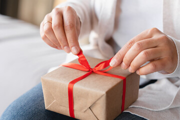 Cropped closeup photo of woman`s hands unwrapping unpacking birthday Christmas present gift box on holiday celebration event.