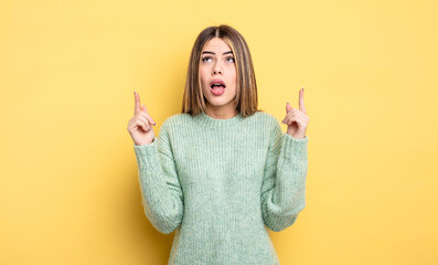 pretty caucasian woman feeling awed and open mouthed pointing upwards with a shocked and surprised...