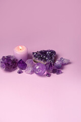 amethyst minerals set and candle on violet background. Magic gemstones for esoteric spiritual...