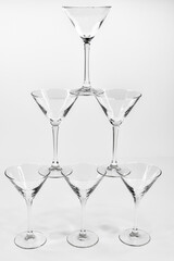 Empty martini cocktail glasses stand on top of each other on white background