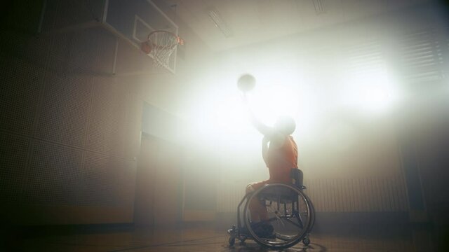 Wheelchair Basketball Player Shooting Ball Successfully through the Basket Net, Scoring a Goal. Determination, Training, Inspiration of Person with Disability. Static Side View Wide Shot, Slow Motion