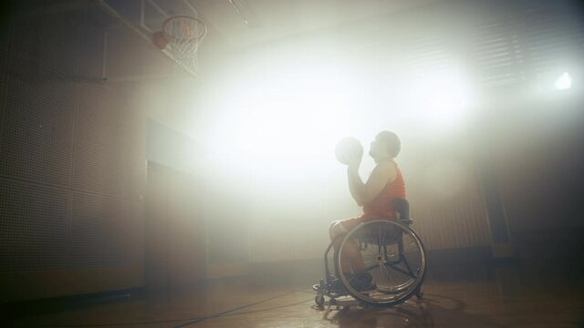 Wheelchair Basketball Player Shooting Ball Successfully through the Basket Net, Scoring a Goal. Determination, Training, Inspiration of Person with Disability. Static Side View Wide Shot, Slow Motion