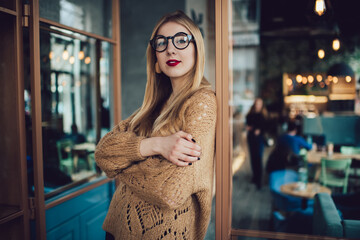 Thoughtful woman looking at camera while resting in cafe