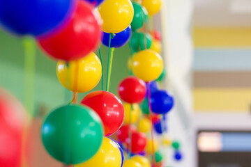 Fototapeta na wymiar Multi-colored plastic balls hang in the children's room. Close plan