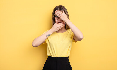 pretty caucasian woman covering face with both hands saying no to the camera! refusing pictures or...