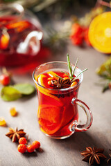 Mulled wine with fruits and spices in glass on a wooden  background. Traditional hot drink at  Autumn time