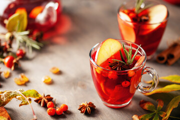 Mulled wine with fruits and spices in glass on a wooden  background. Traditional hot drink at ...