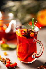 Mulled wine with fruits and spices in glass on a wooden  background. Traditional hot drink at  Autumn time