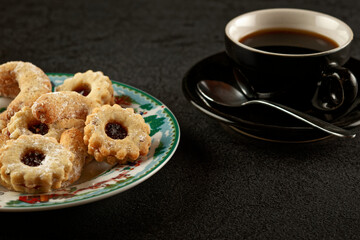Christmas cookies on a plate, next to a cup of espresso coffee. 
