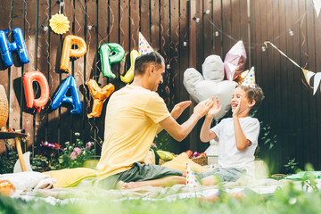 Father and son have fun and playing together at funny birthday celebration in cottage yard in summer.