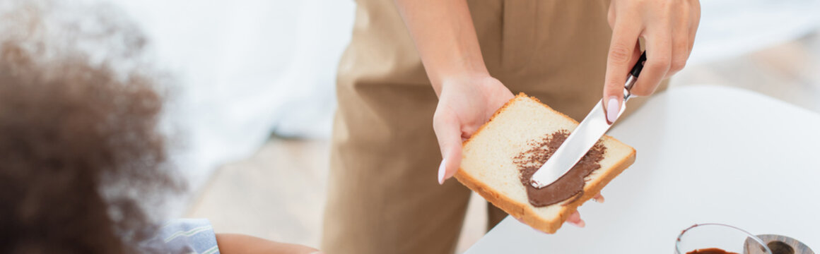 Cropped View Of African American Mother Making Toast With Chocolate Paste Near Kid, Banner.